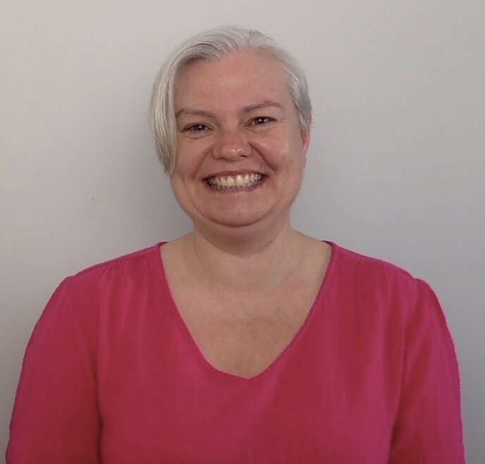 Jodie Thornton smiling with grey hair and a hot pink shirt